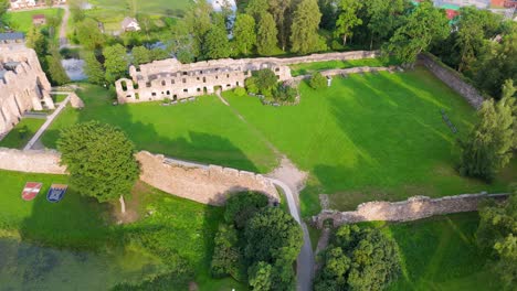 aerial view of dobele castle ruins, flowing berze river and illuminated fountains at sunset serene latvian summer evening from above, scenic aerial of latvian historical landscape in golden hour