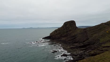 rickets head rising aerial drone shot with crashing waves and dramtic coastline in pembrokeshire uk 4k