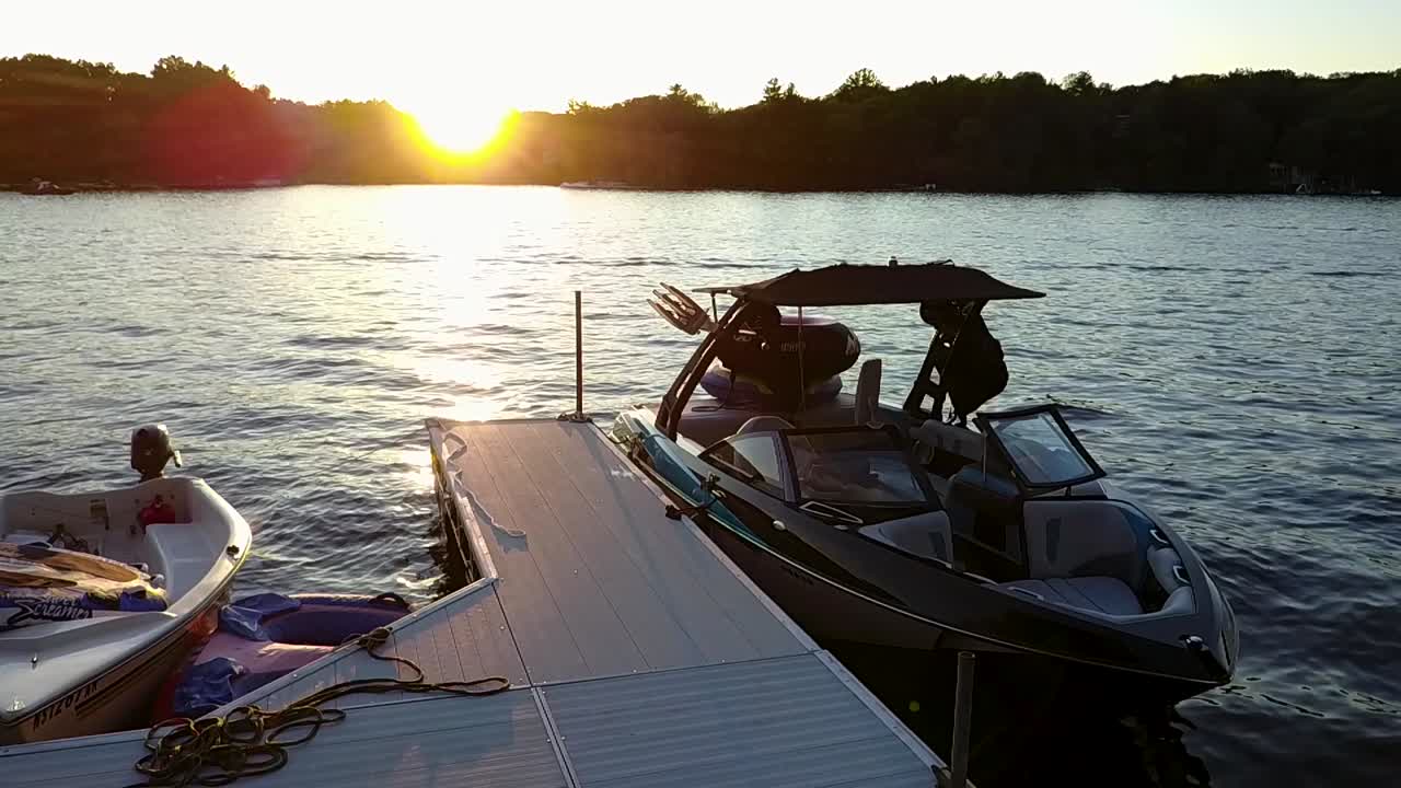 Video walking along a dock past a boat towards a lake sunset