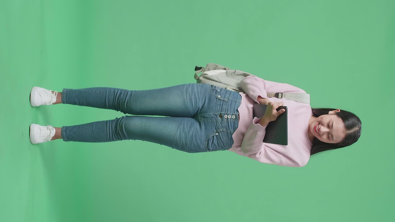 Full Body Of Asian Woman Student Using Tablet On Green Screen Studio