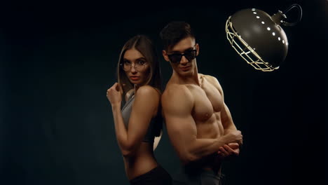 fit couple posing back-to-back in studio
