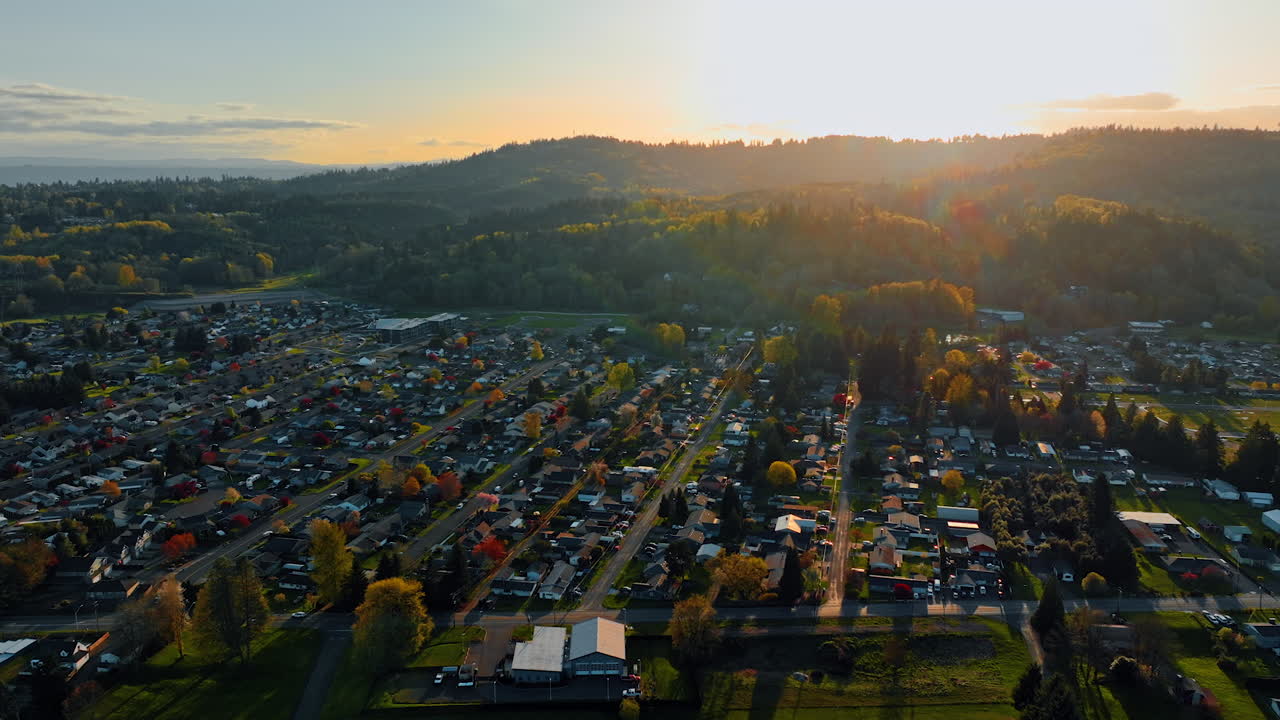 Cozy town with lots of greenery at the foot of the mountains. Sun hiding behind the rocks lighting the rural area. Top view.