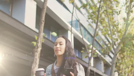 Video-De-Luces-De-Colores-Sobre-Una-Mujer-Birracial-Caminando-Al-Trabajo,-Usando-Un-Teléfono-Inteligente-En-La-Calle