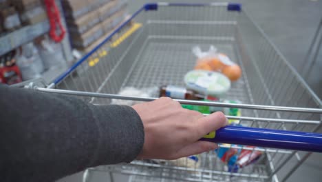 a shopping basket in hand in a grocery hypermarket. selective focus.