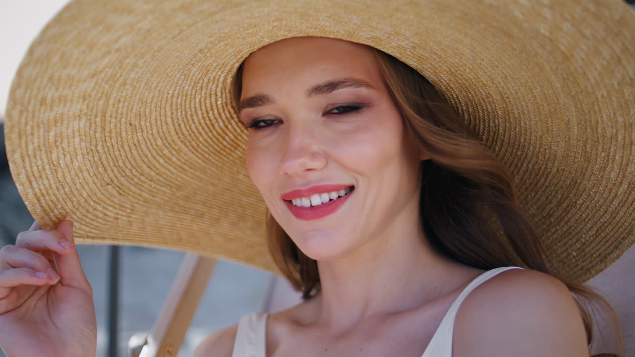 Portrait brunette sitting beach taking off sunglasses. Happy woman posing coast