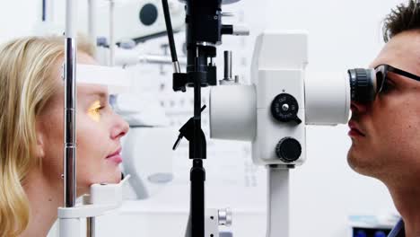 optometrist examining female patient on slit lamp