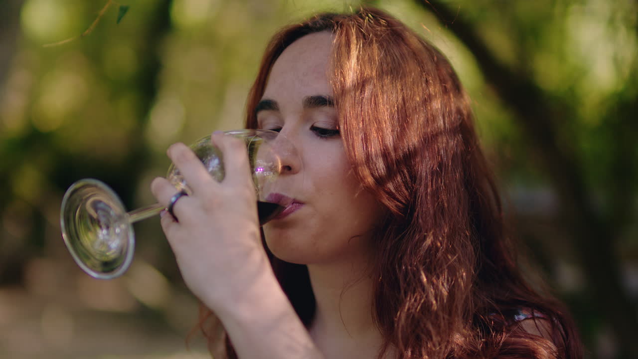 chica prueba un vaso de vino en un parque de picnic cerca de la toma