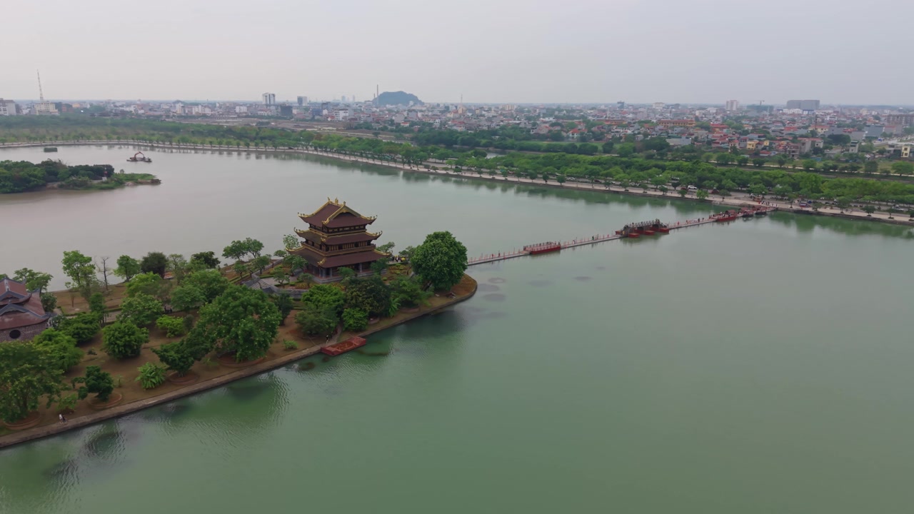 Ninh Binh, Vietnam'da sakin sularla çevrili küçük bir adada bulunan Chua Vang Budist tapınağını gösteren drone görüntüleri