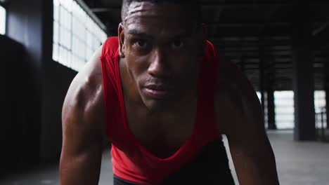 portrait of african american man kneeling starting a run in an empty building