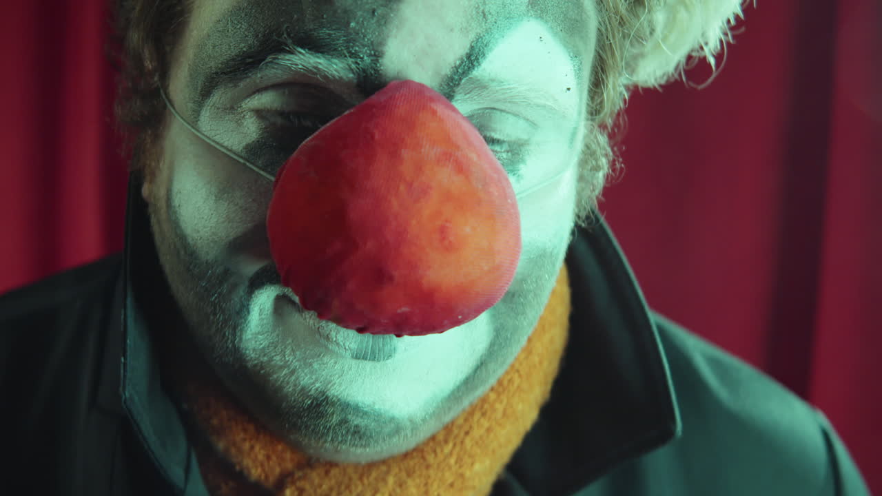 retrato de un payaso triste contra la cortina roja del escenario