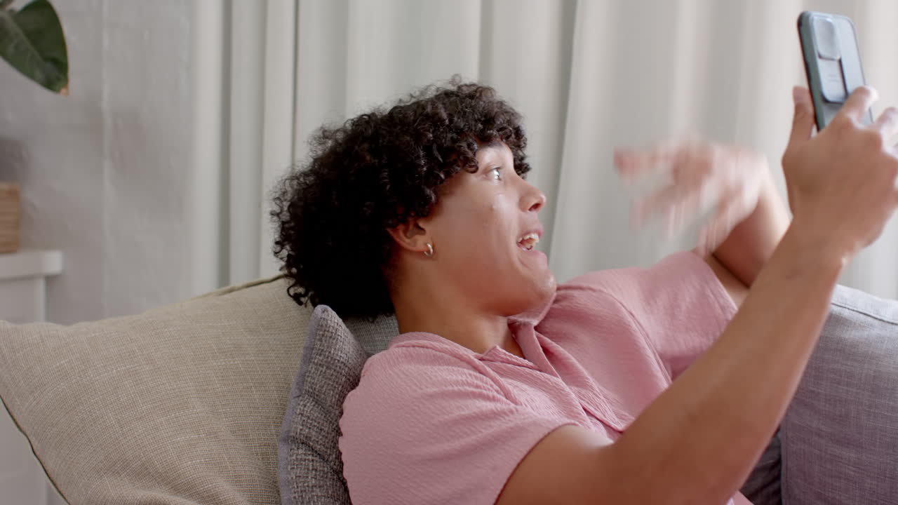 Young man on couch making having video chat on smartphone, at home