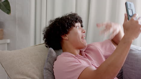 young man on couch making having video chat on smartphone, at home