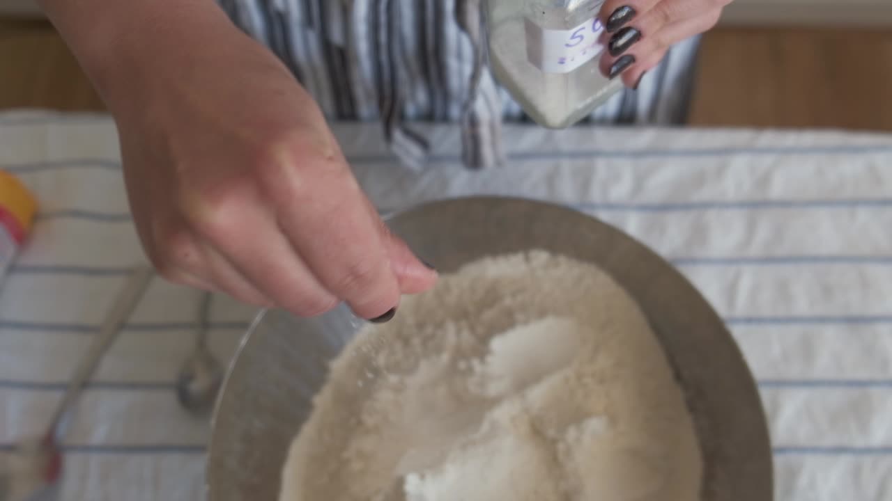 반죽을 준비하고 소금을 넣는 여자