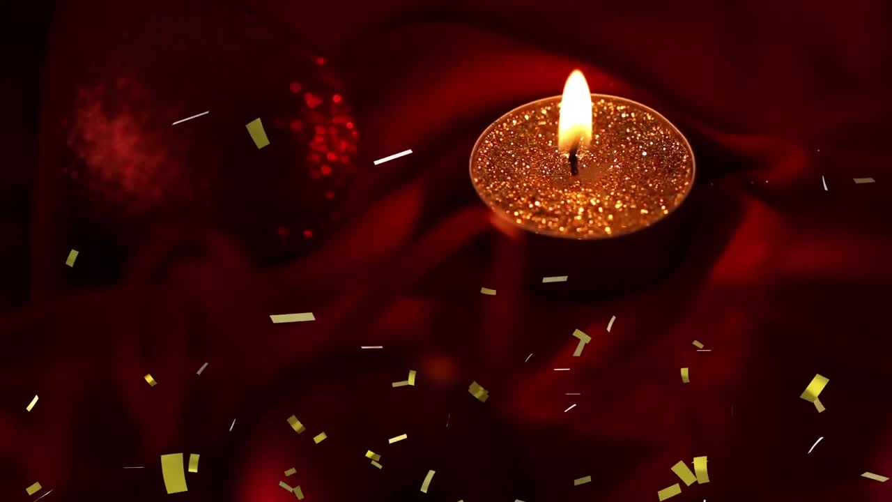 Animazione di coriandoli dorati che cadono su una candela tea light accesa su sfondo scuro