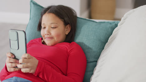 Video-De-Una-Feliz-Chica-Asiática-Descansando-En-Un-Sofá-Con-Un-Teléfono-Inteligente