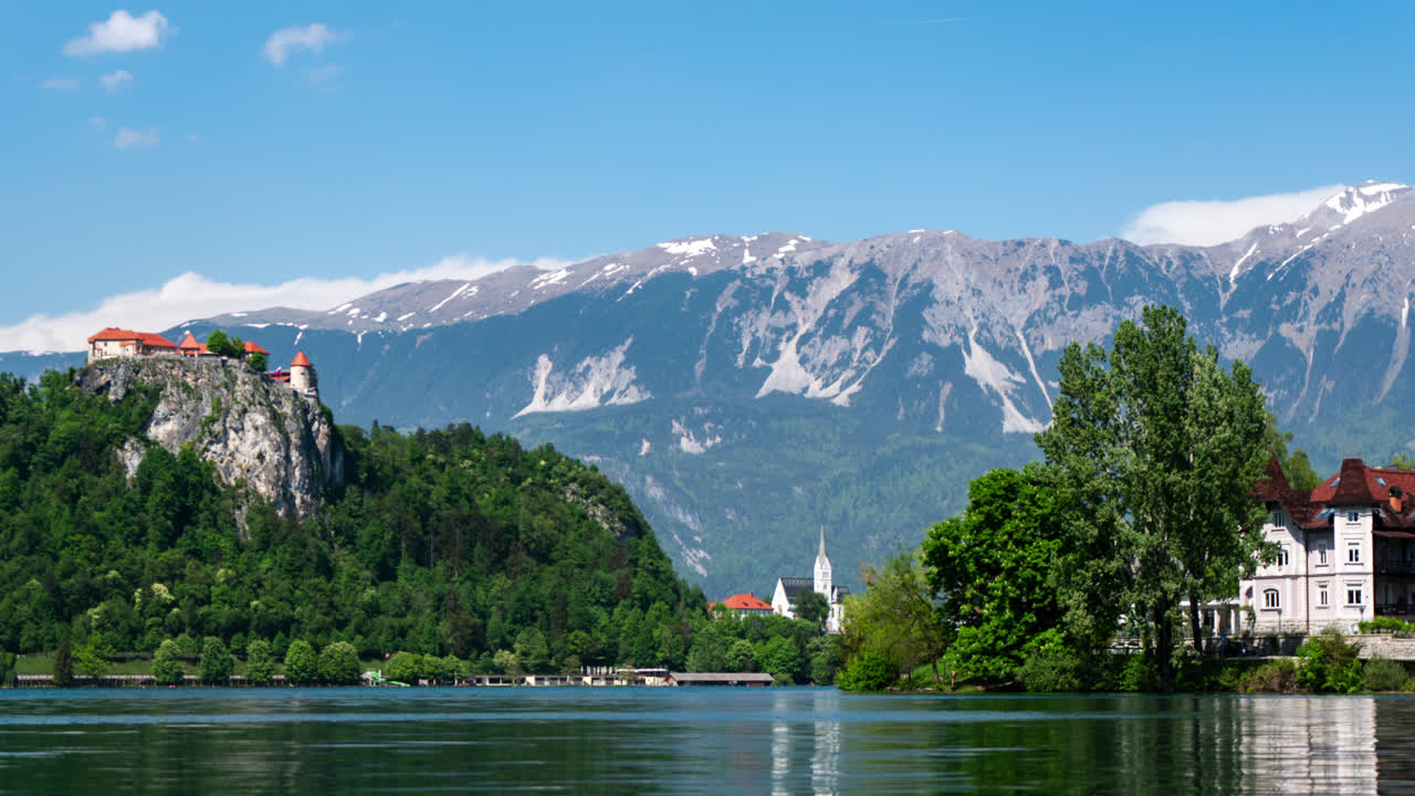 time lapse of lake Bled Slovenia castle on top of a cliff with mountains in background and clouds forming