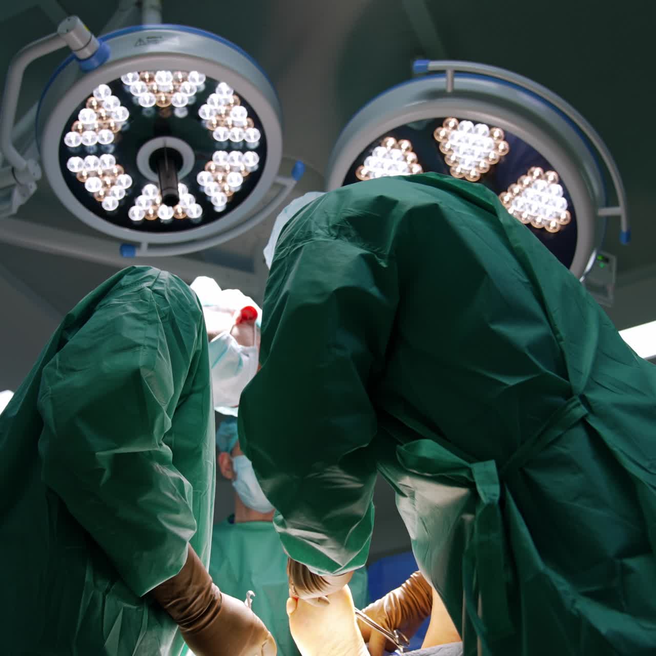 Due chirurghi ortopedici eseguono un intervento chirurgico al piede. I medici utilizzano strumenti in metallo. Angolazione dal basso