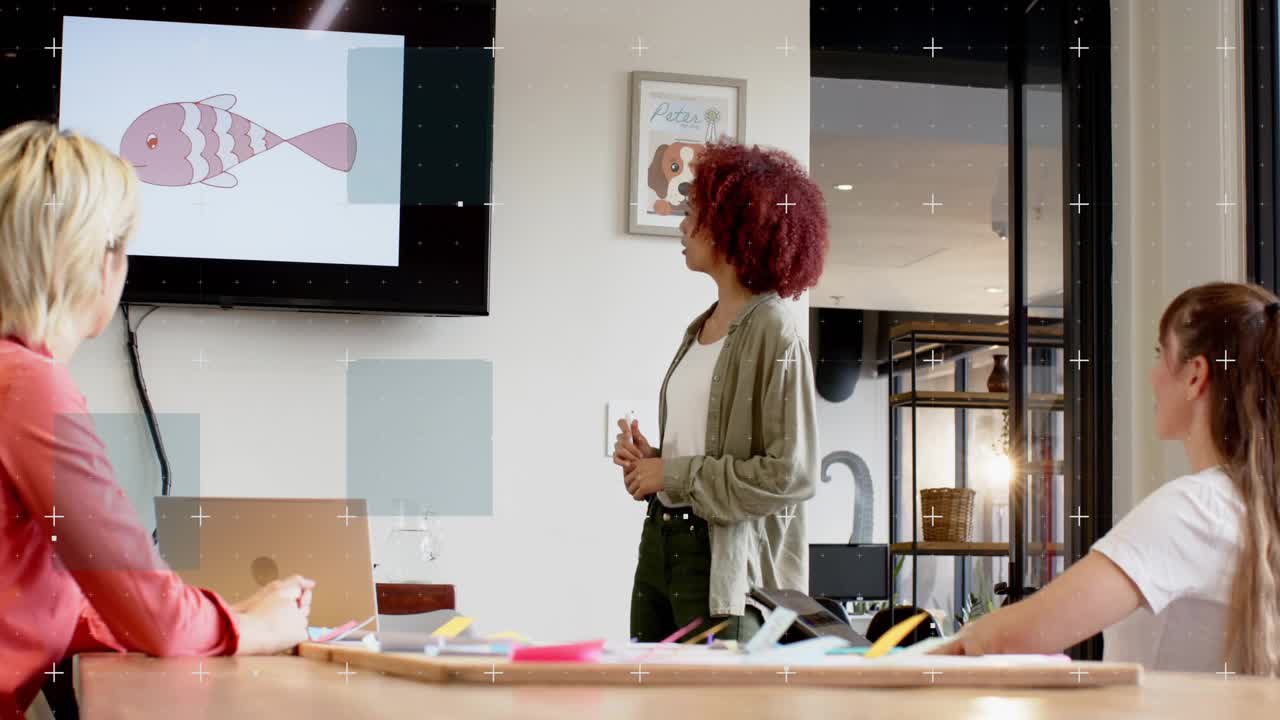 Presenter tapping monitor and pointing at pink fish, leading design review while team taking notes