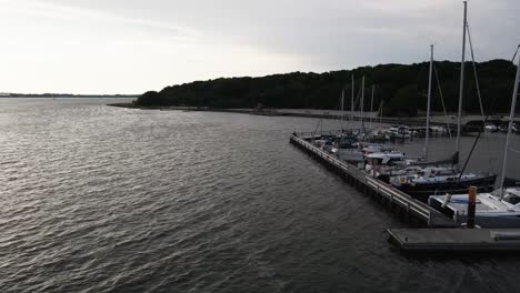 Aerial:-Flying-next-to-a-small-harbour-with-fishing-boats-into-the-sunset