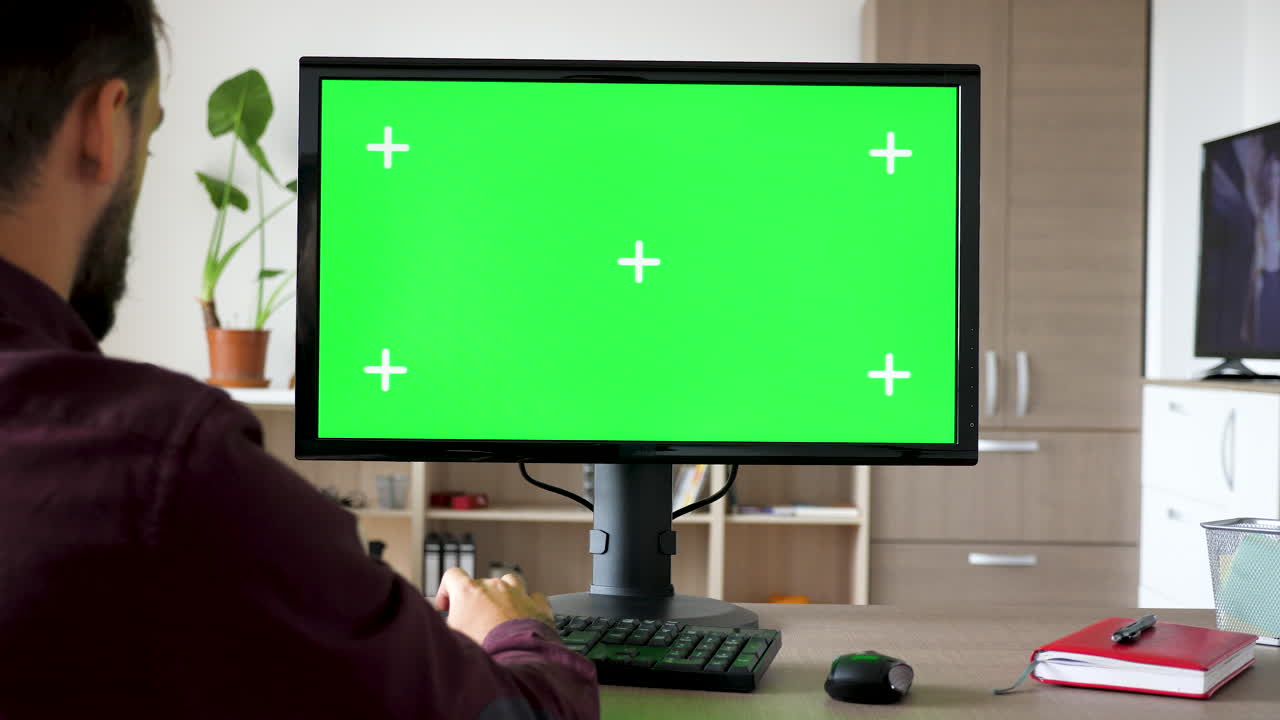 hombre trabajando en la computadora con pantalla verde