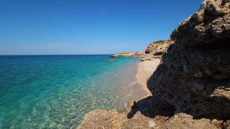 Glänzender-Morgen-Am-Paradiesischen-Strand-Zwischen-Den-Klippen,-Die-An-Einem-Sommerurlaub-An-Der-Albanischen-Küste-Vom-Blau-türkisen-Meer-Umspült-Werden