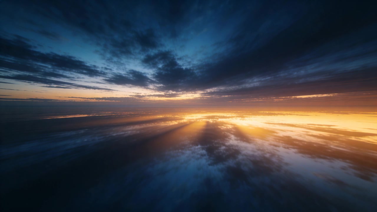 Revealing sun approaching horizon from aerial view, band casting golden rays across low cloud layer