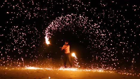 el intérprete muestra habilidades de fuego en la playa de arena