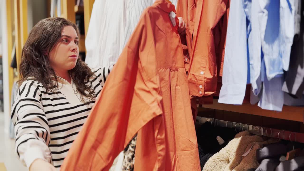 Young woman choosing clothes in fashion store