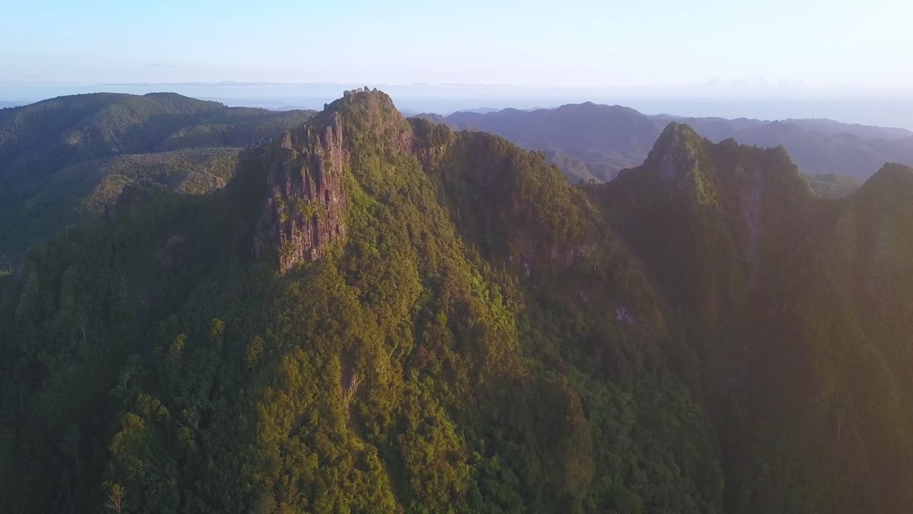 volando junto a pináculos irregulares en las cadenas montañosas de coromandel en una mañana soleada, nueva zelanda