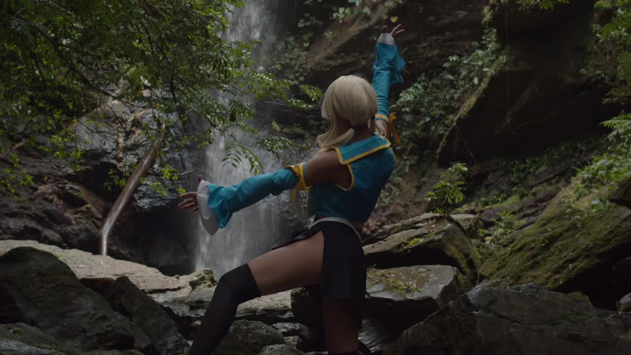 ubicación épica de la cascada en la naturaleza con un cosplayer de anime en primer plano