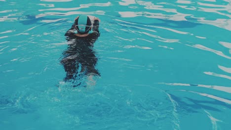 Rückansicht-Einer-Asiatischen-Frau,-Die-Schwimmen-Lernt-Und-Ein-Schwimmbrett-Mit-Beinen-Hält,-Die-Im-Schwimmbad-Arbeiten