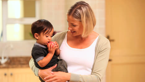 Baby-in-his-mothers-arms-trying-to-eat-an-apple-