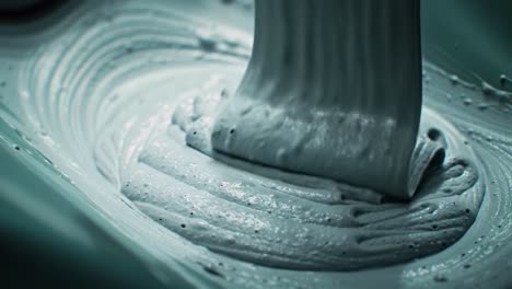 an artist skillfully blends paint in a studio setting, creating a smooth and even texture. the rhythmic motion of the mixing process enhances the vibrant color preparation.