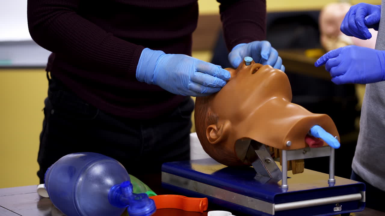 Dummy head and intubation set for advance cardiac life support training. Detailed training medical equipment. Two medics on first aid training.