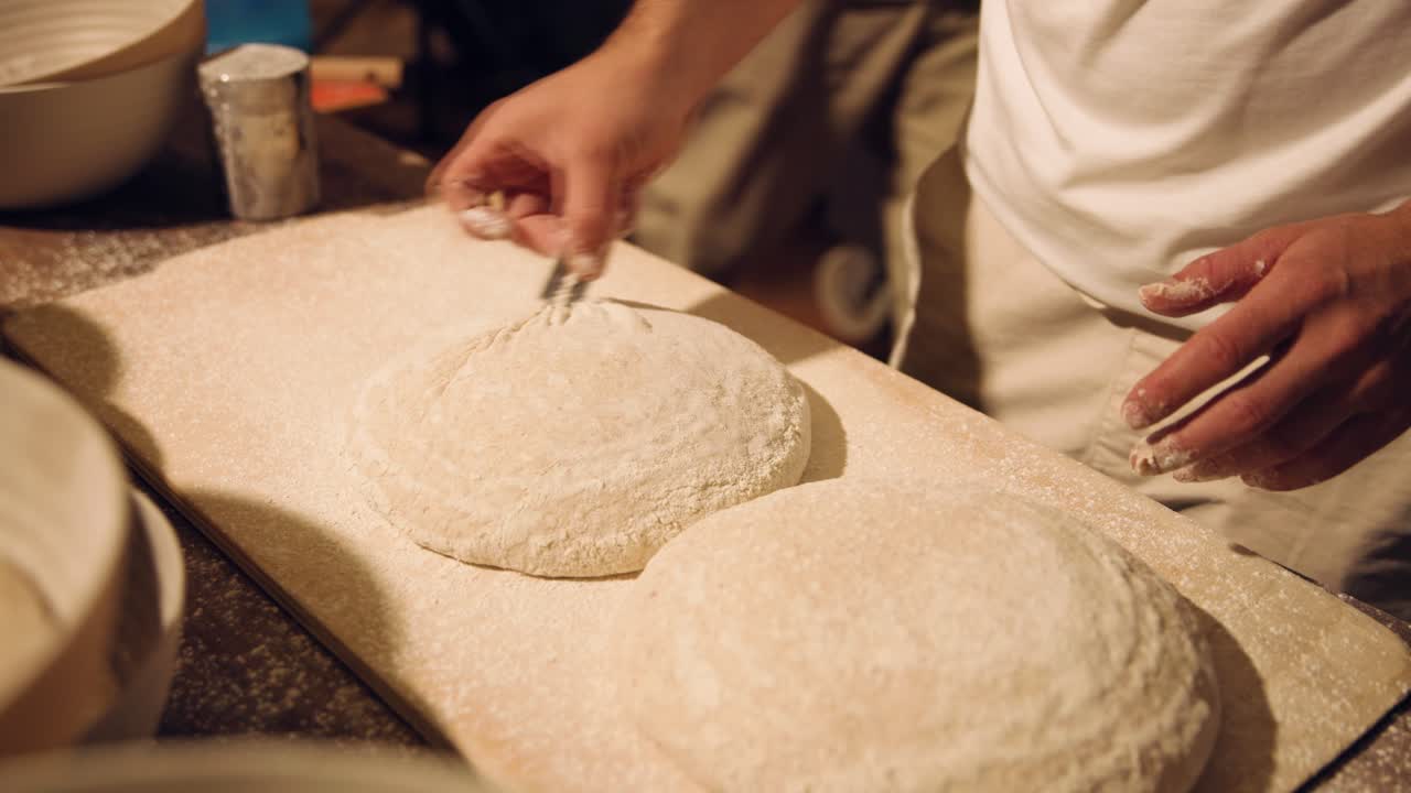 Panettiere che incide l'impasto appena preparato con farina su un tagliere di legno