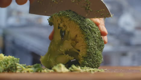 cut with a knife on a wooden board closeup broccoli in the kitchen. shred