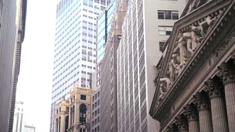 low angle pan right view of skyscrapers lining wall street in new york city