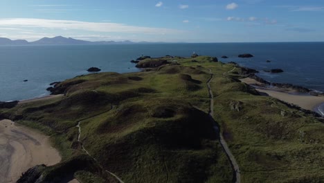 aerial view descending to ynys llandwyn lush vibrant coastal tide island overlooking misty sunrise snowdonia mountain range