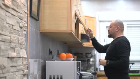 a man opens the kitchen unit to take and put back a stemware