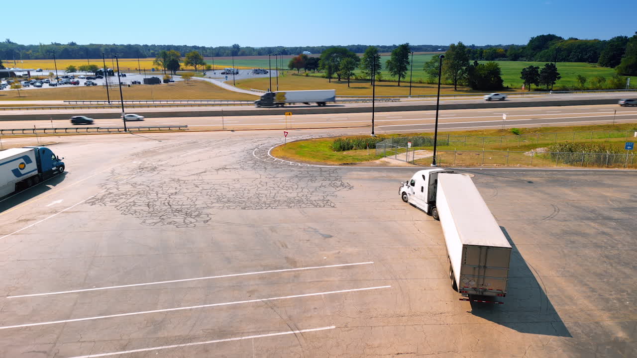 Chicago, USA, 29 June 2025: A long white truck turns to drive to the road. Lively traffic on the highway at backdrop. Aerial view