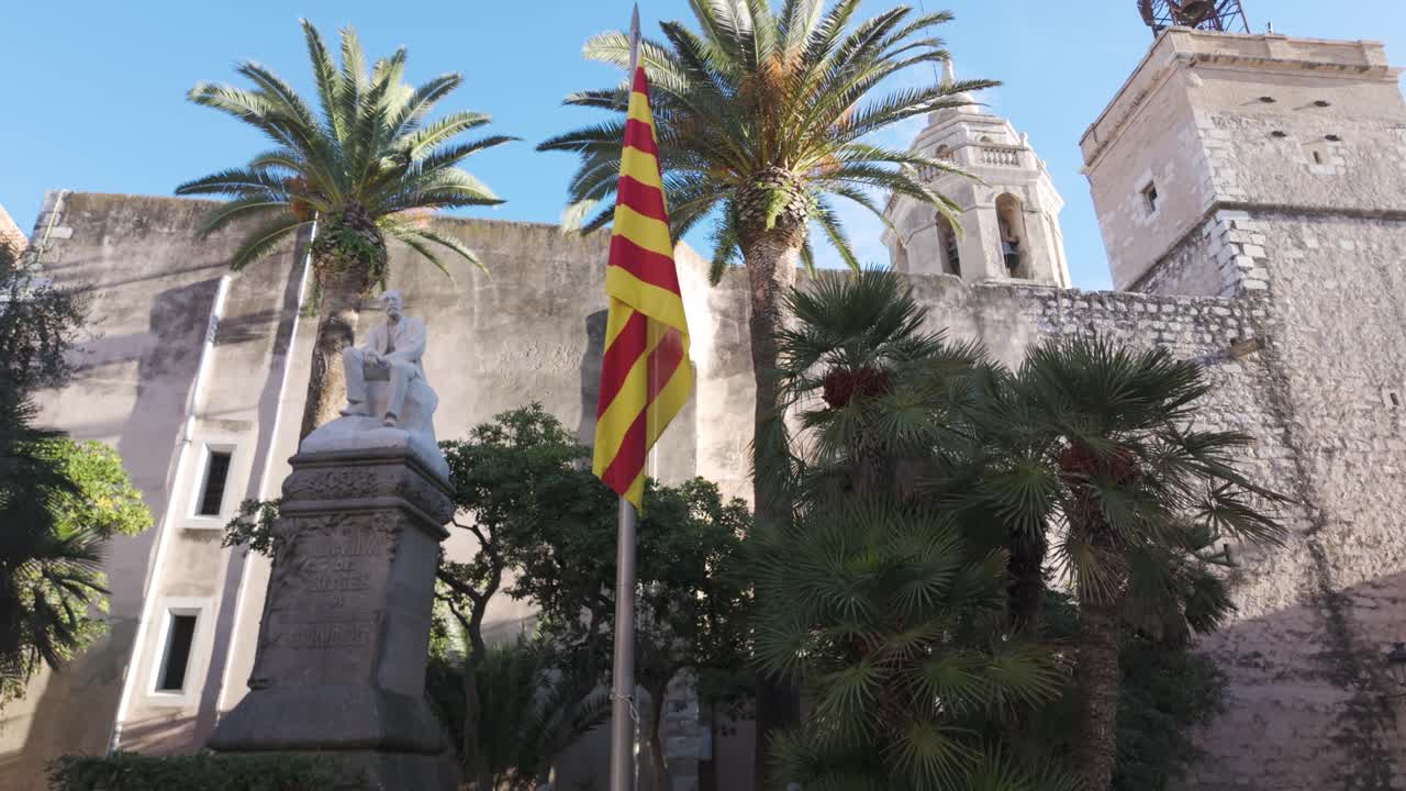 Baroque-style Iglesia de San Bartolomé exhibits historical architecture with statues and palm trees in a serene town square under a clear blue sky, offering cultural and visually striking elements.