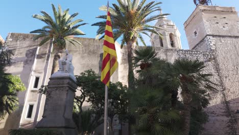 baroque-style iglesia de san bartolomé exhibits historical architecture with statues and palm trees in a serene town square under a clear blue sky, offering cultural and visually striking elements.