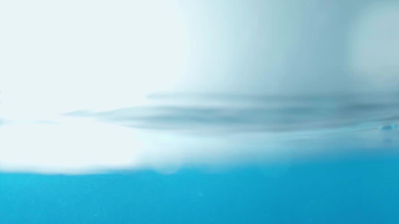 슬로우 모션의 깨끗한 물 표면은 물이 튀는 상점으로 화면을 채우고 기포로 액체 표면을 흔들고 있습니다.