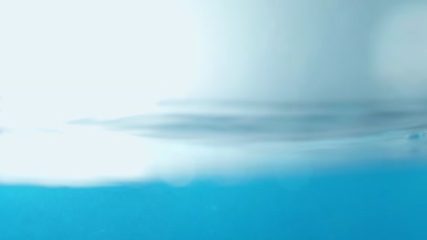 la superficie del agua limpia en cámara lenta llena la pantalla con agua salpicando la gota de agua y la superficie líquida ondeando con una burbuja de aire