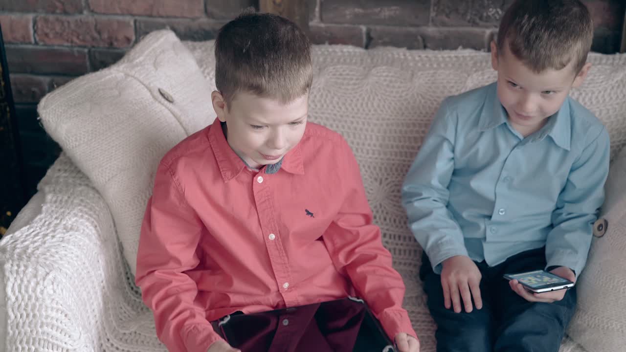 boy watches little brother playing games on smartphone