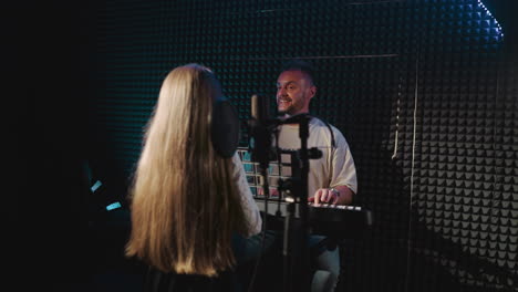 teacher rehearses song with child in music studio. smiling father plays piano and looks at little daughter dancing in sound insulated room. creative family