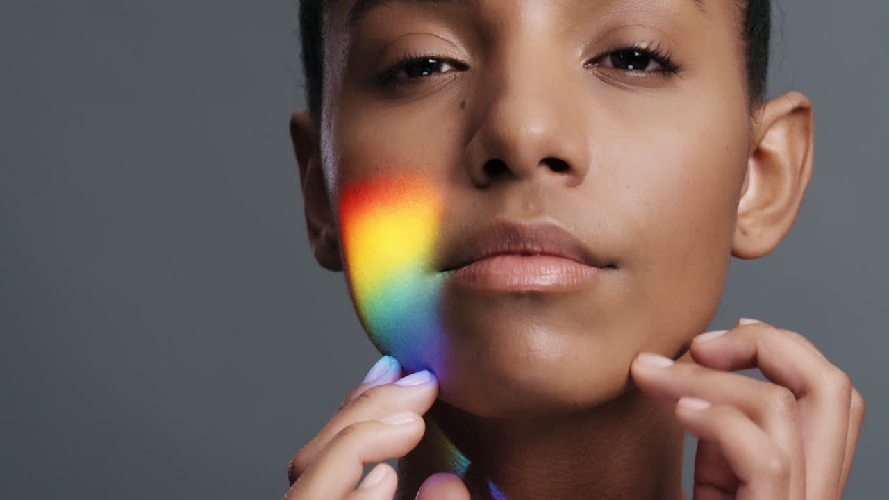 retrato multicolor de cerca hermosa mujer afroamericana tocando el rostro acariciando la piel suave disfrutando del cuidado de la piel belleza con luz colorida que se refleja en la tez suave