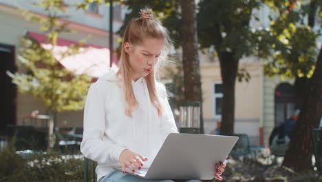 young woman using laptop loses becoming surprised by sudden lottery results loss fail in street