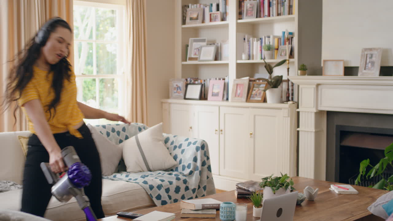 행복한 십대 소녀 집에서 춤을 추고 헤드폰을 착용하고 진공청소기를 사용하고 재미있는 춤을 추고 음악을 듣고 집을 청소하고 주말에 집안일을 즐기고 무모한 라이프 스타일을 축하합니다.