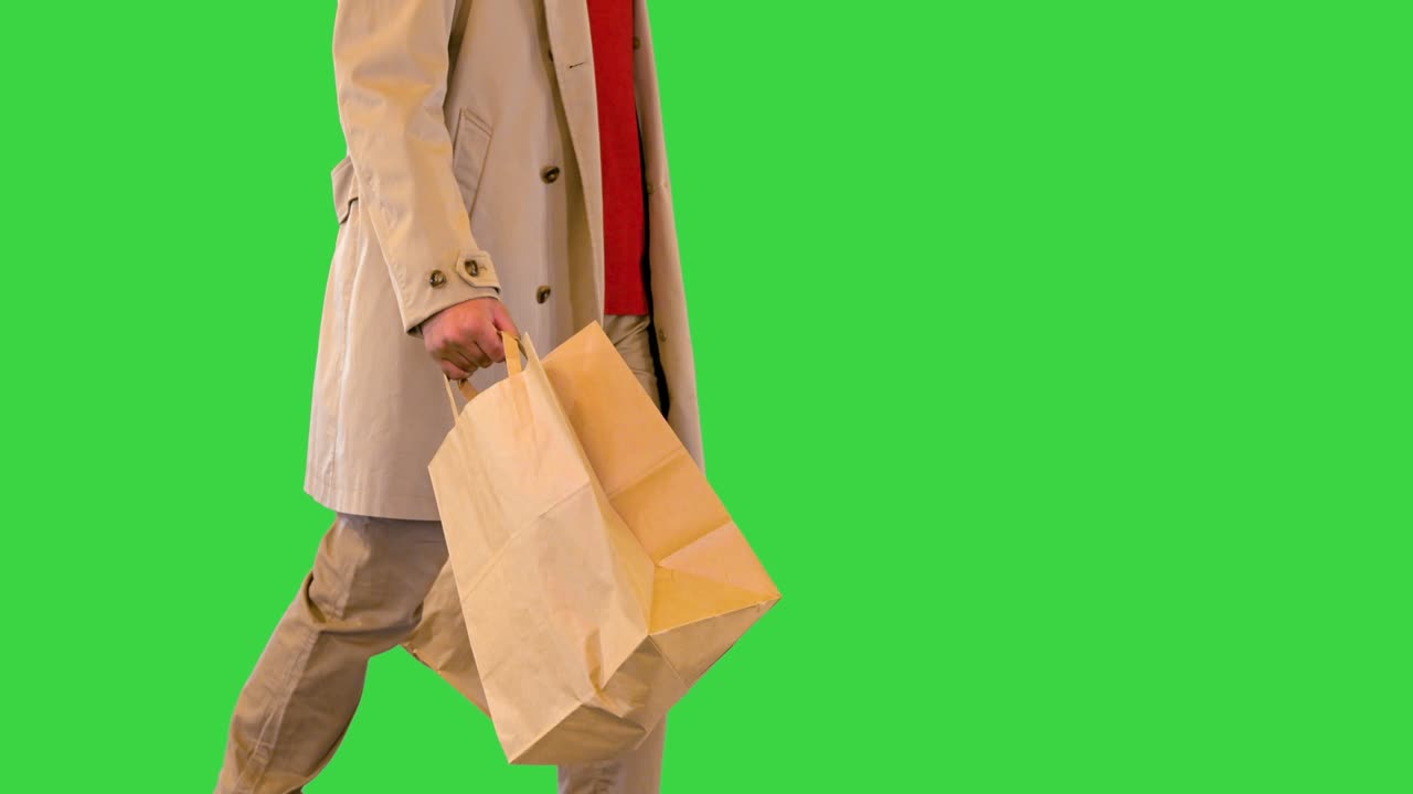 남성 고객은 녹색 화면, 크로마 키에서 소매점 또는 부티크에서 패션 옷과 함께 종이 쇼핑 가방을 들고 있습니다.